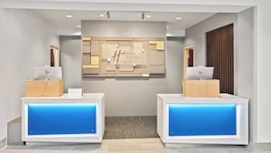 A reception area with two reception desks, a central wall with a Holiday Inn Express sign, and a wooden panel design.