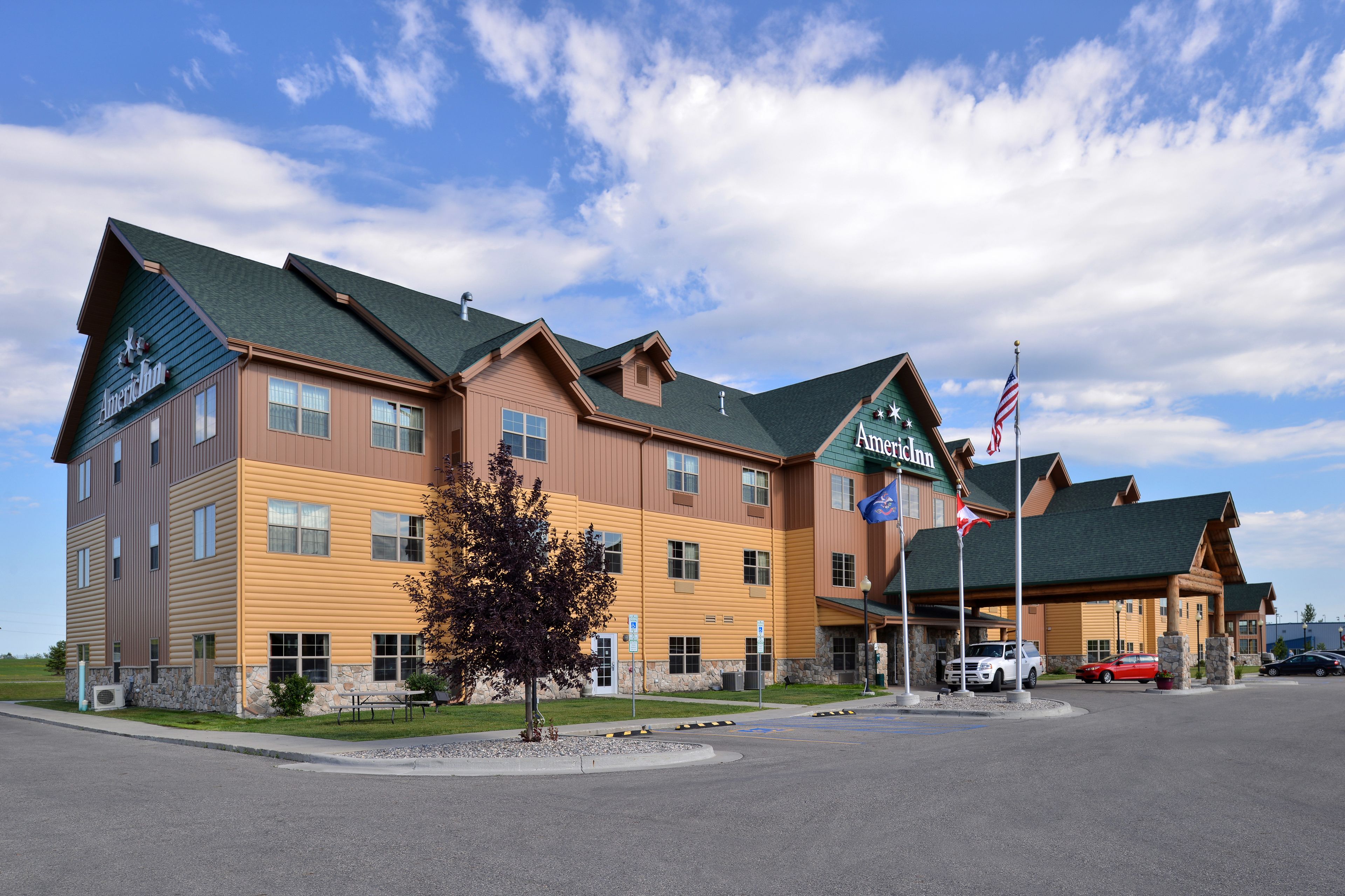 A multi-story hotel with a green roof, American flags, and a parking lot.