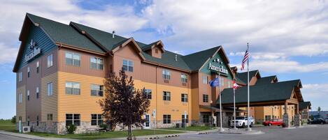 A multi-story hotel with a green roof, American flags, and a parking lot.