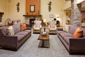 Cozy living room with a stone fireplace, two sofas, and a large mirror.