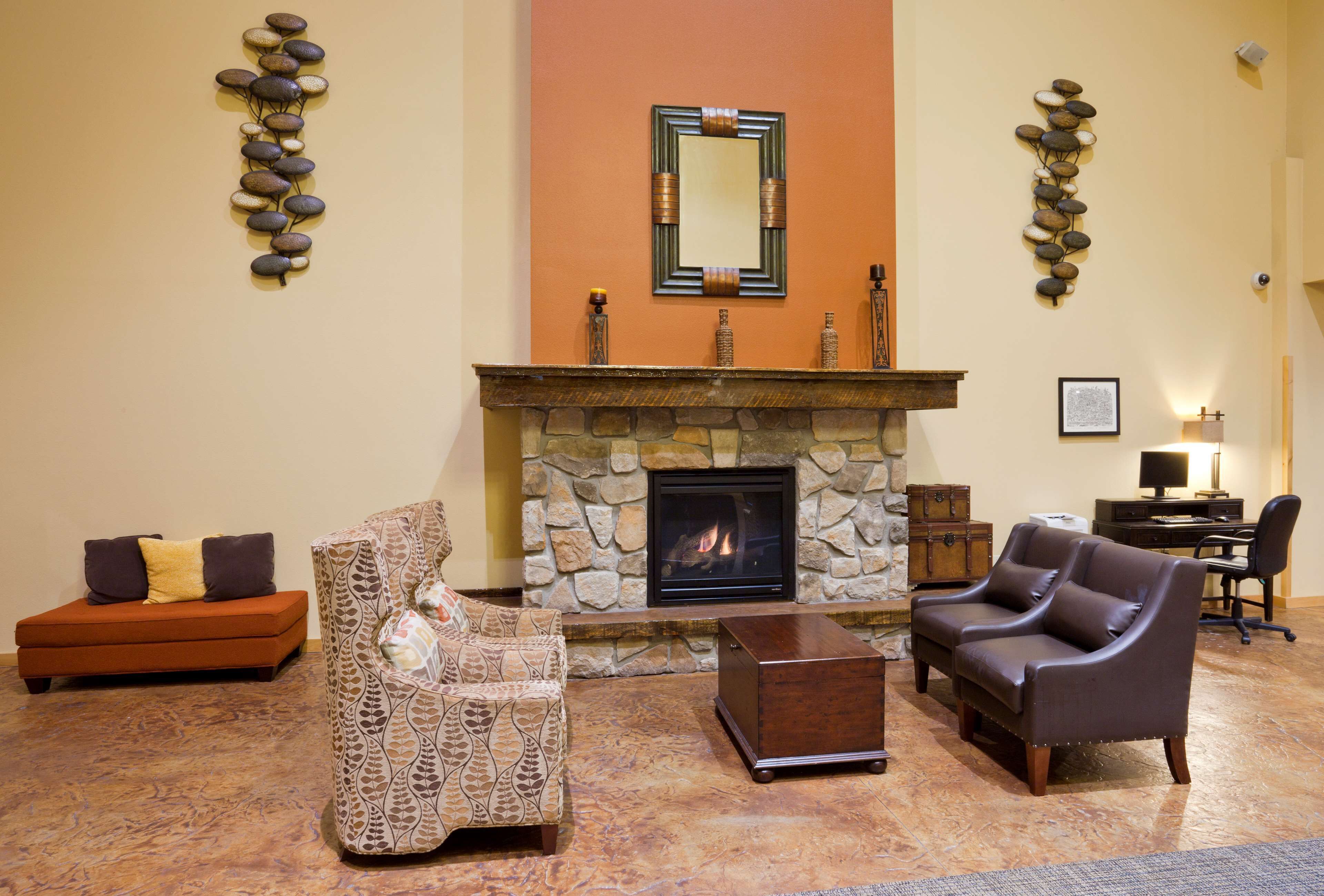 Una sala de estar con chimenea de piedra, dos sofás, una mesa de centro y decoración en las paredes.
