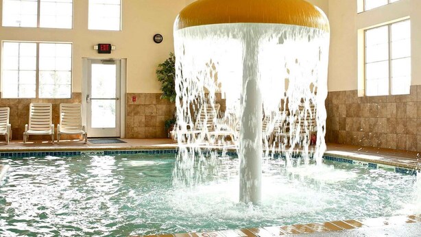 Une piscine agrémentée d’une fontaine centrale, dotée d’un intérieur lumineux et d’un espace détente.