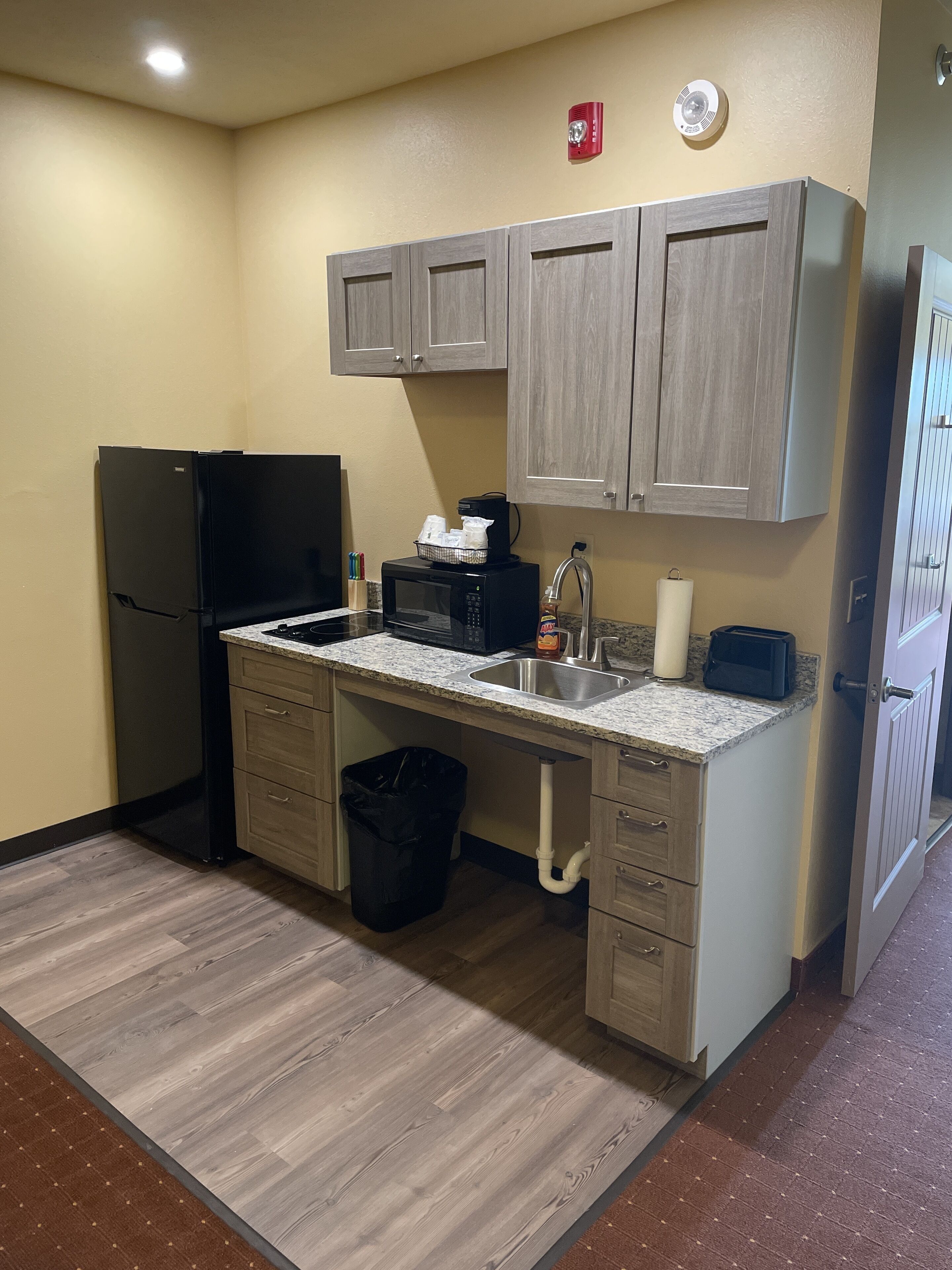 A compact kitchen with a refrigerator, microwave, sink, and cabinets.