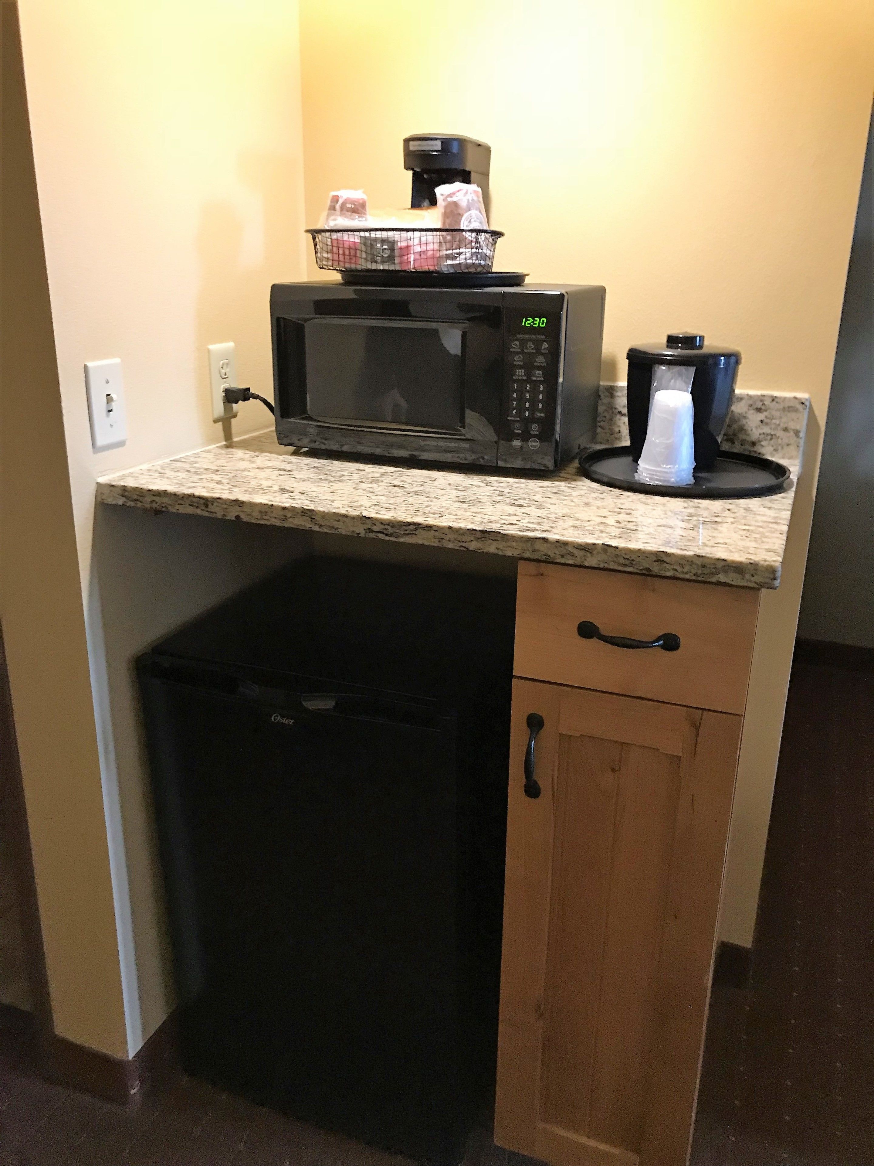 A kitchen with a microwave, coffee maker, and a trash bin.