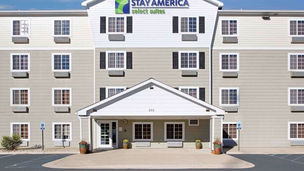 Un hotel de varios pisos con fachada plana, una entrada central y un letrero que dice "Extended Stay America Select Suites".