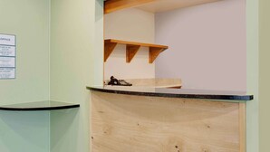 Zona de recepción con mostrador de madera, teléfono y cartel con horarios de registro de entrada y salida.