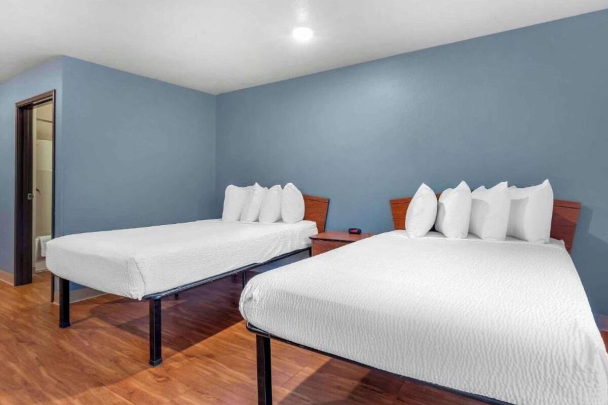 A room with two beds, wooden flooring, and blue walls.