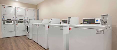 A laundry facility with multiple washing machines and dryers, a control panel, and a digital display.