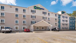 Een Stay America hotel met een centrale ingang, meerdere verdiepingen en een parkeerplaats.