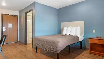 A bedroom with a bed, a wooden chair, a nightstand, and a door.