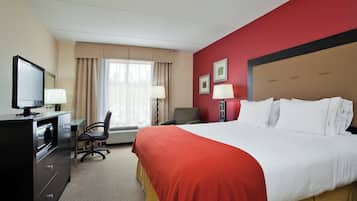 A hotel room with a bed, desk, chair, television, and two lamps.