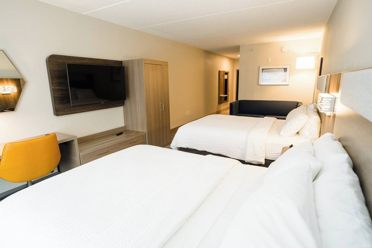 Una camera d'albergo con due letti, una televisione, una scrivania con una sedia e un armadio.