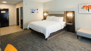 Een hotelkamer met een groot bed, nachtkastjes, een stoel en een houten vloer.