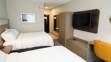 Habitación de hotel con dos camas, televisión, armario y escritorio con silla.