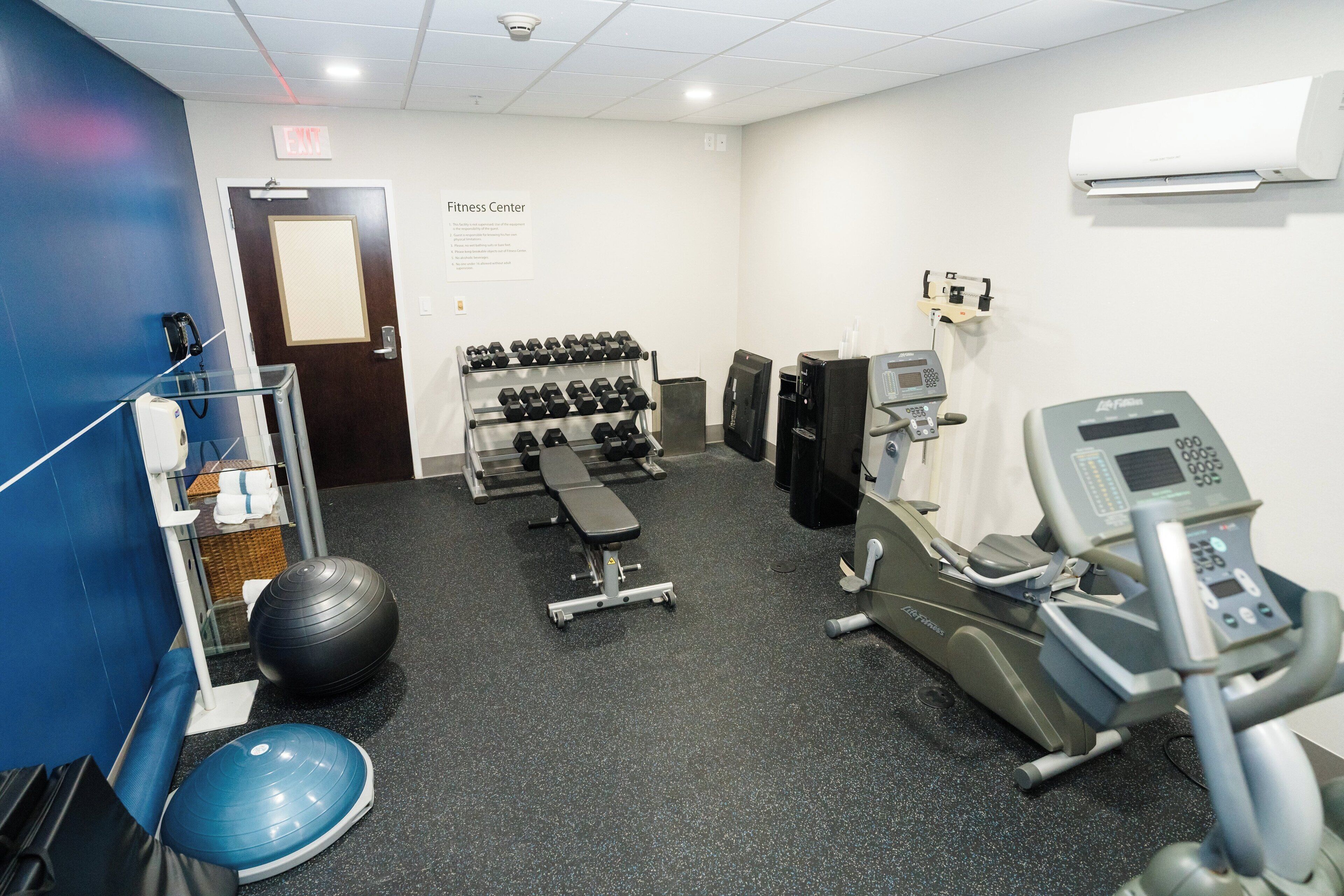 Une salle de sport équipée de matériel d’exercice, d’un banc, d’haltères et d’un vélo d’appartement.