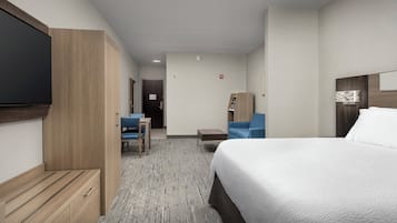 A hotel room with a bed, a desk, a chair, and a TV.
