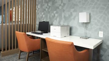 A modern office space with a white desk, two orange chairs, a printer, and a lamp.