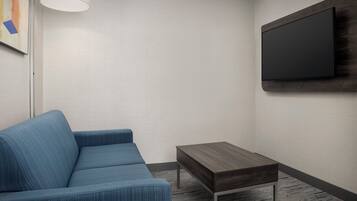 A modern living room with a blue sofa, a small wooden table, and a mounted TV on the wall.