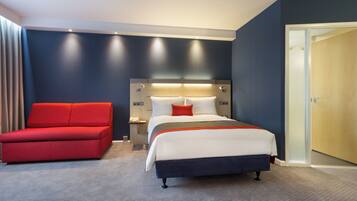 Una habitación de hotel con una cama, una silla roja, una mesita de noche y una puerta.