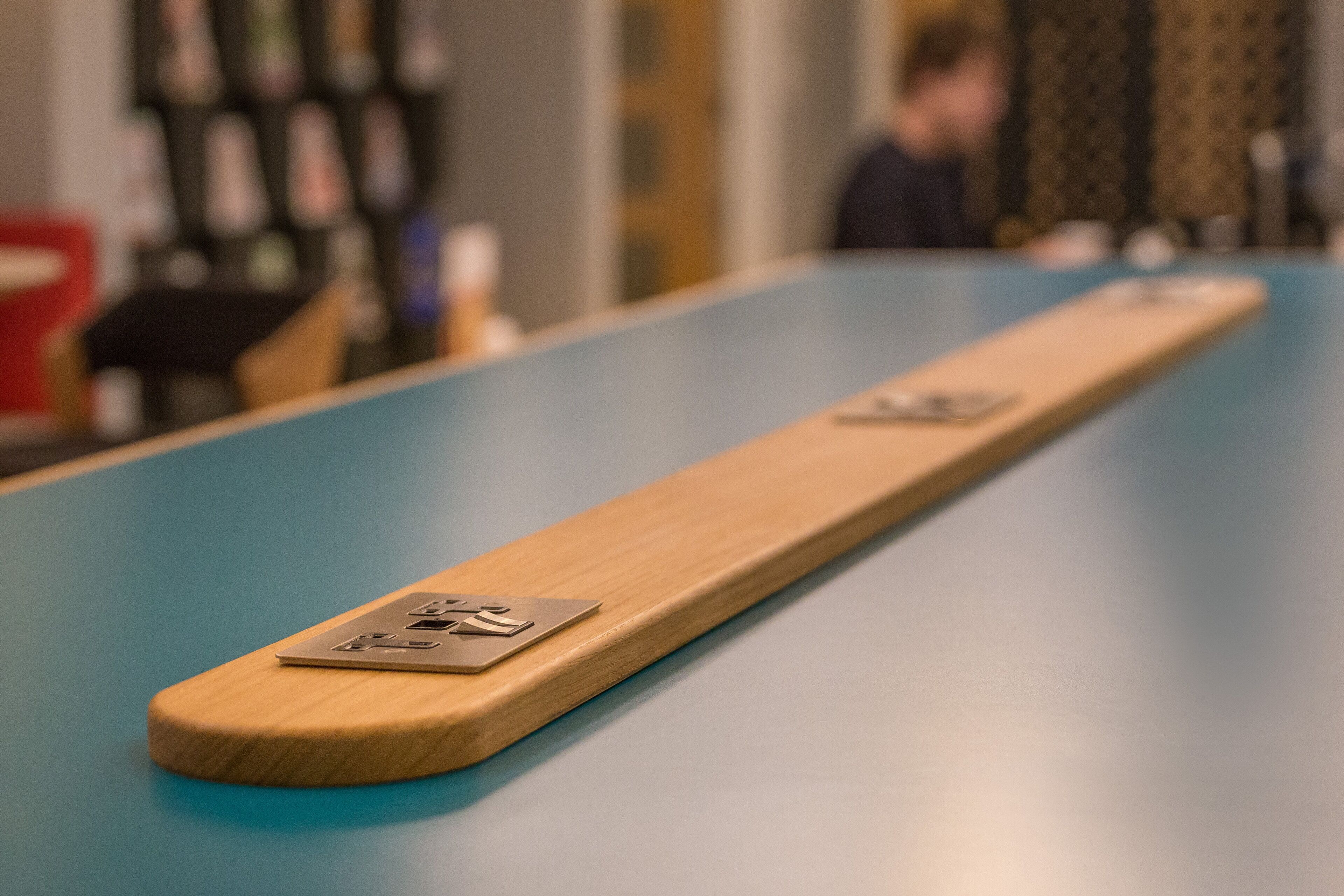 A long, narrow wooden table with a metal plate on one end.