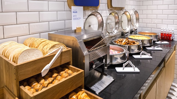 Un buffet proposant une variété de plats, notamment du pain, des pâtisseries et des plats chauds.