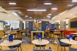 A modern indoor dining area with wooden tables and chairs, a pool table, and a bar area. - Holiday Inn Express London-Watford Junction by IHG (Watford)