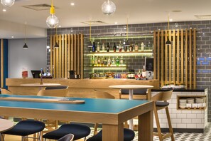 A modern bar area with a counter, seating, and a variety of bottles. - Holiday Inn Express London-Watford Junction by IHG (Watford)