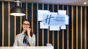 Un comptoir d’accueil d’hôtel au design moderne, avec un mur revêtu de panneaux en bois et une enseigne « Holiday Inn Express ».