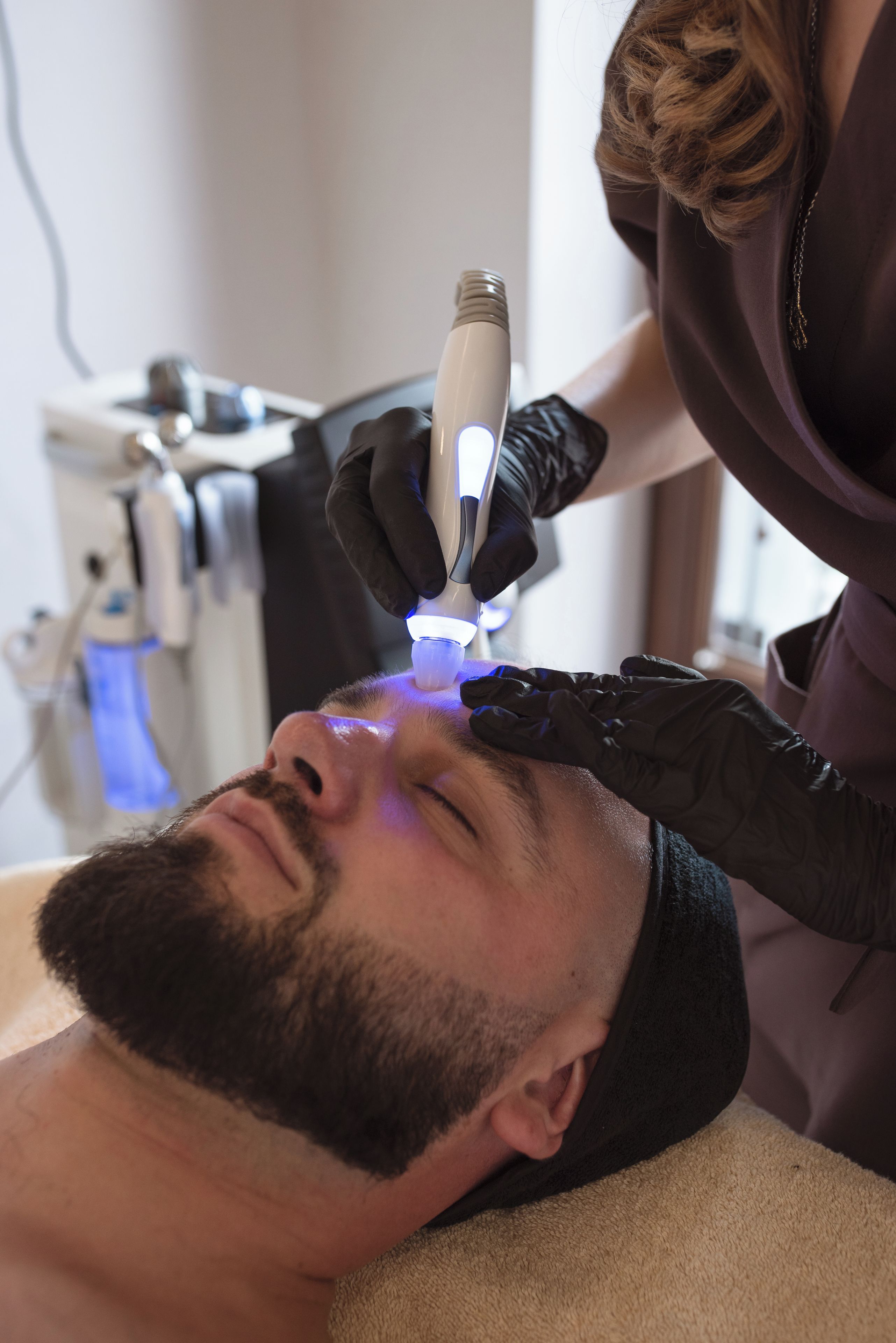 A person lying down with a medical device being used on their face.