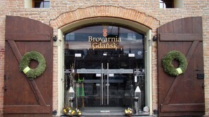 Un edificio de ladrillo con dos grandes puertas de madera, cada una decorada con un adorno. Encima de la entrada se muestra el nombre "Brovarnia Gdańsk".