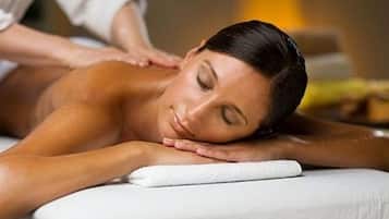 En person får massage på ett vitt massagebord i ett rum med en neutral färgskala.