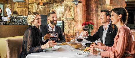 Un groupe de personnes est réuni dans un restaurant dont l’intérieur est de style rustique, avec des murs en briques apparentes et des poutres en bois.