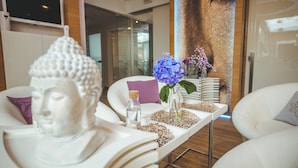 Un interior moderno con un sofá blanco, una mesa con una estatua de Buda, un florero con flores y un mural grande en la pared.