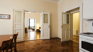 A kitchen with wooden flooring, a stove, and a dining area with chairs. - Sibelius Apartments Prague - Art Nouveau Residence 1902 (Prague)