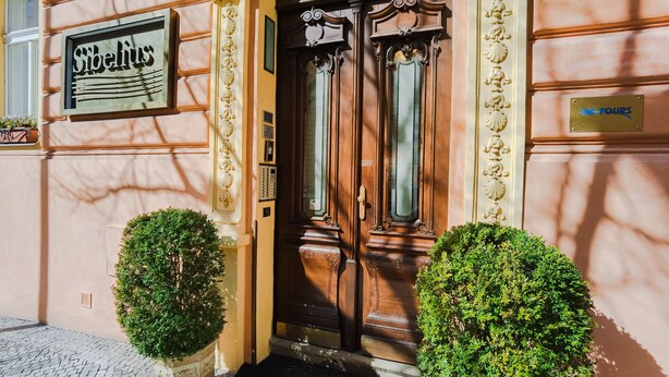 A building entrance with a sign reading "Sibelius" and a plaque labeled "ONE TOURS." - Sibelius Apartments Prague - Art Nouveau Residence 1902 (Prague)