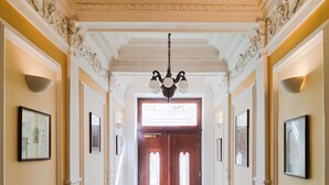 A hallway with a patterned floor, a chandelier, and framed pictures on the walls. - Sibelius Apartments Prague - Art Nouveau Residence 1902 (Prague)