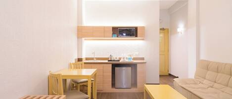 Un espacio habitable compacto con kitchenette, comedor y zona de estar.