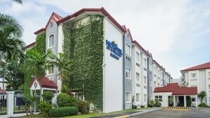 Un hotel de varios pisos con un letrero llamativo que dice 'MICROTEL BY WYNDHAM BATANGAS'.