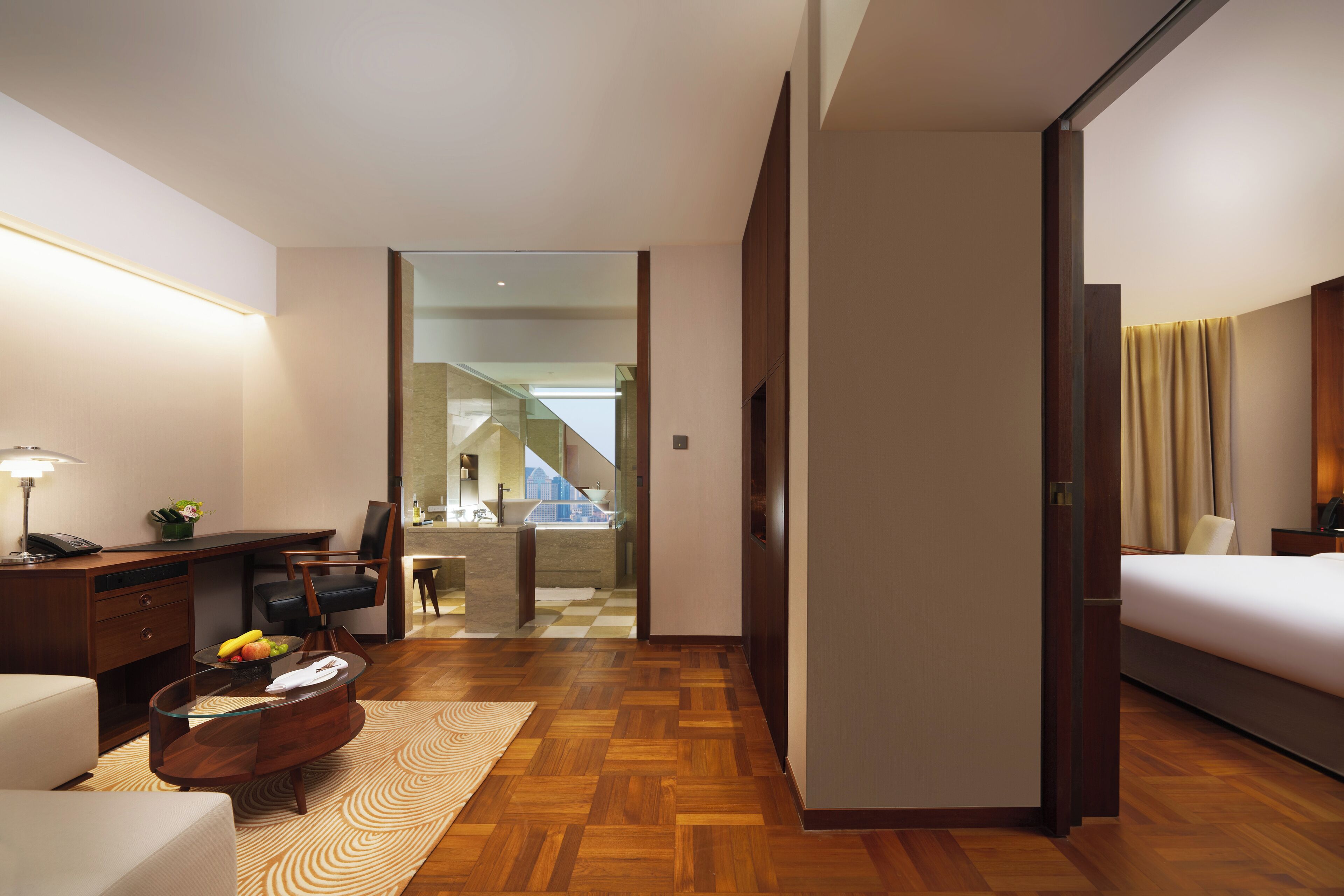 Habitación de hotel con cama, escritorio, silla y vista a una escalera que conduce a un balcón.