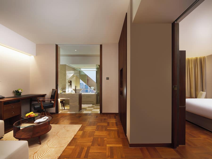 Habitación de hotel con cama, escritorio, silla y vista a una escalera que conduce a un balcón.