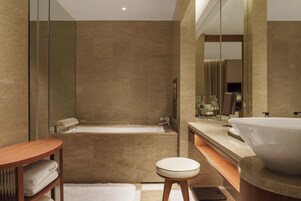 A modern bathroom with a bathtub, a large sink, and a mirror.