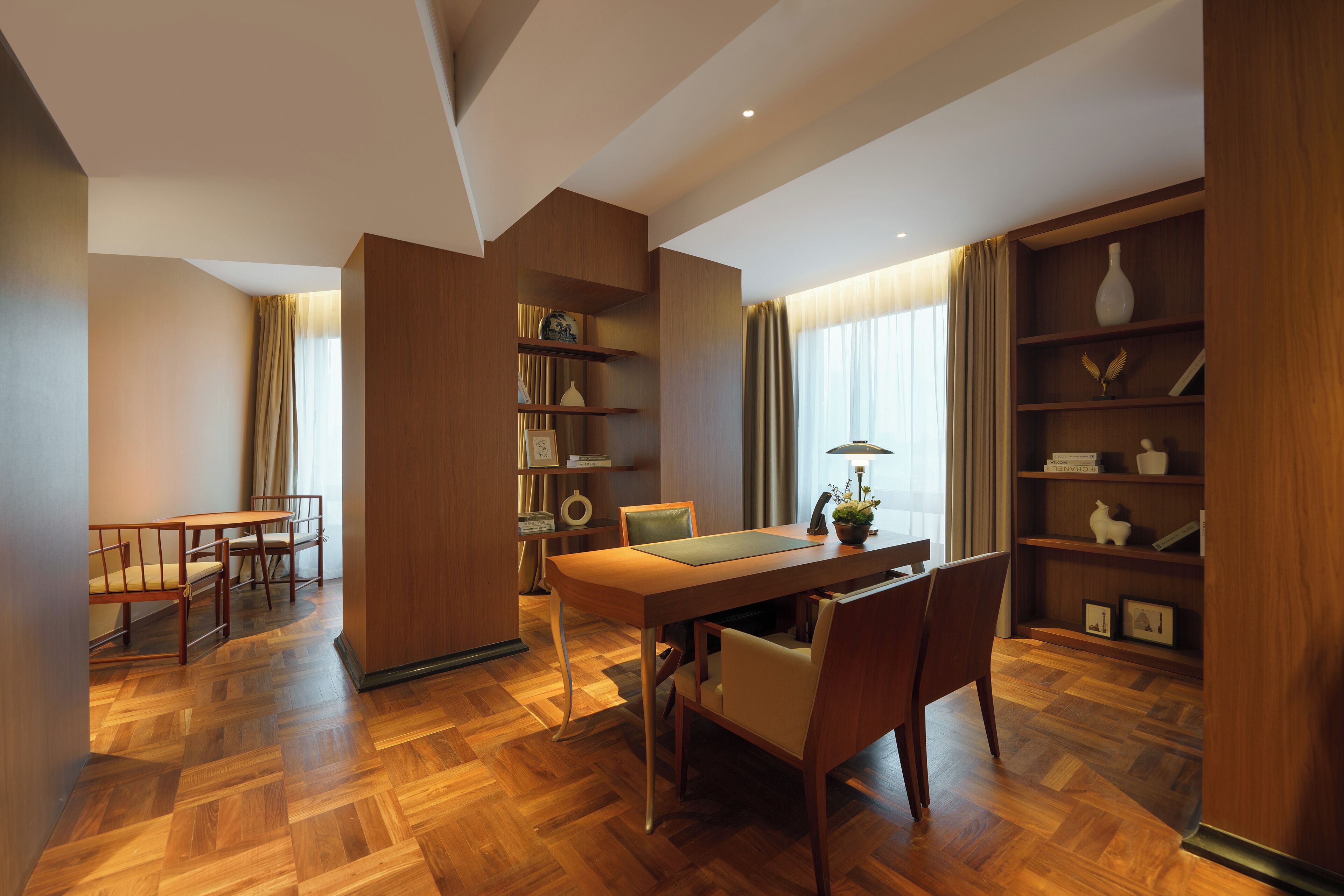 A dining area with a wooden table and chairs, a bookshelf, and a potted plant.