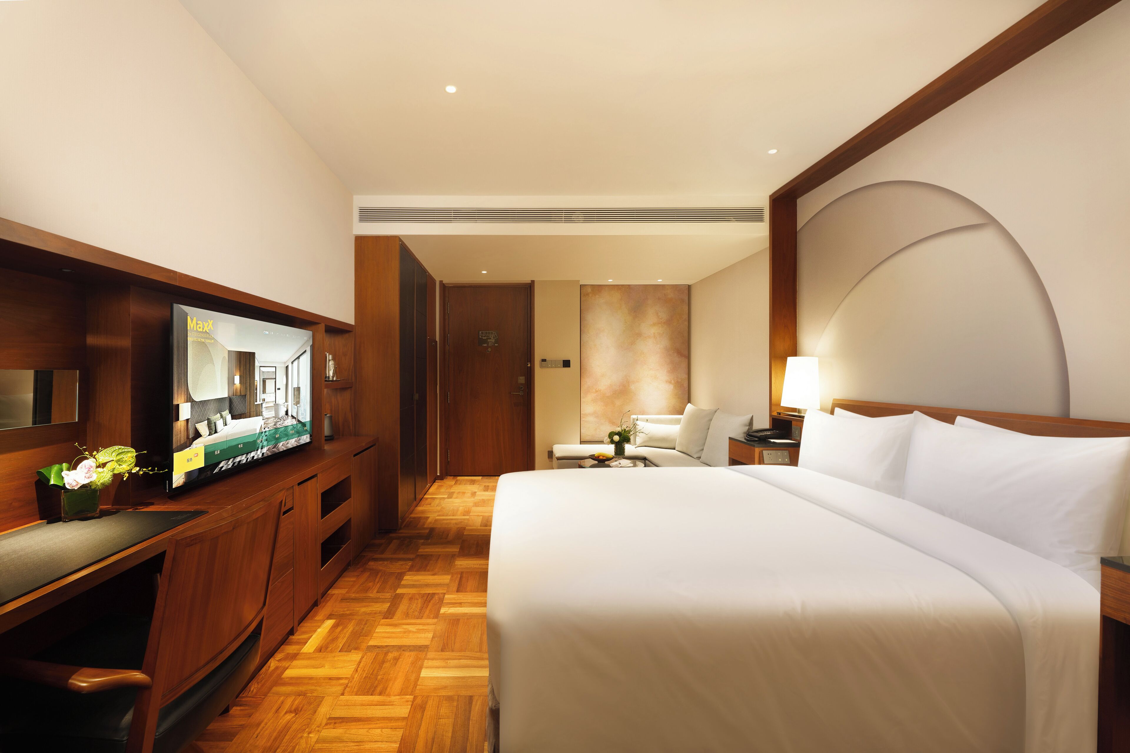 Una habitación de hotel con cama, televisor, escritorio y silla.