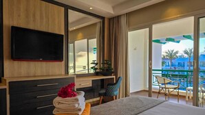 A hotel room with a bed, a desk, a chair, a TV, and a balcony with a pool view.