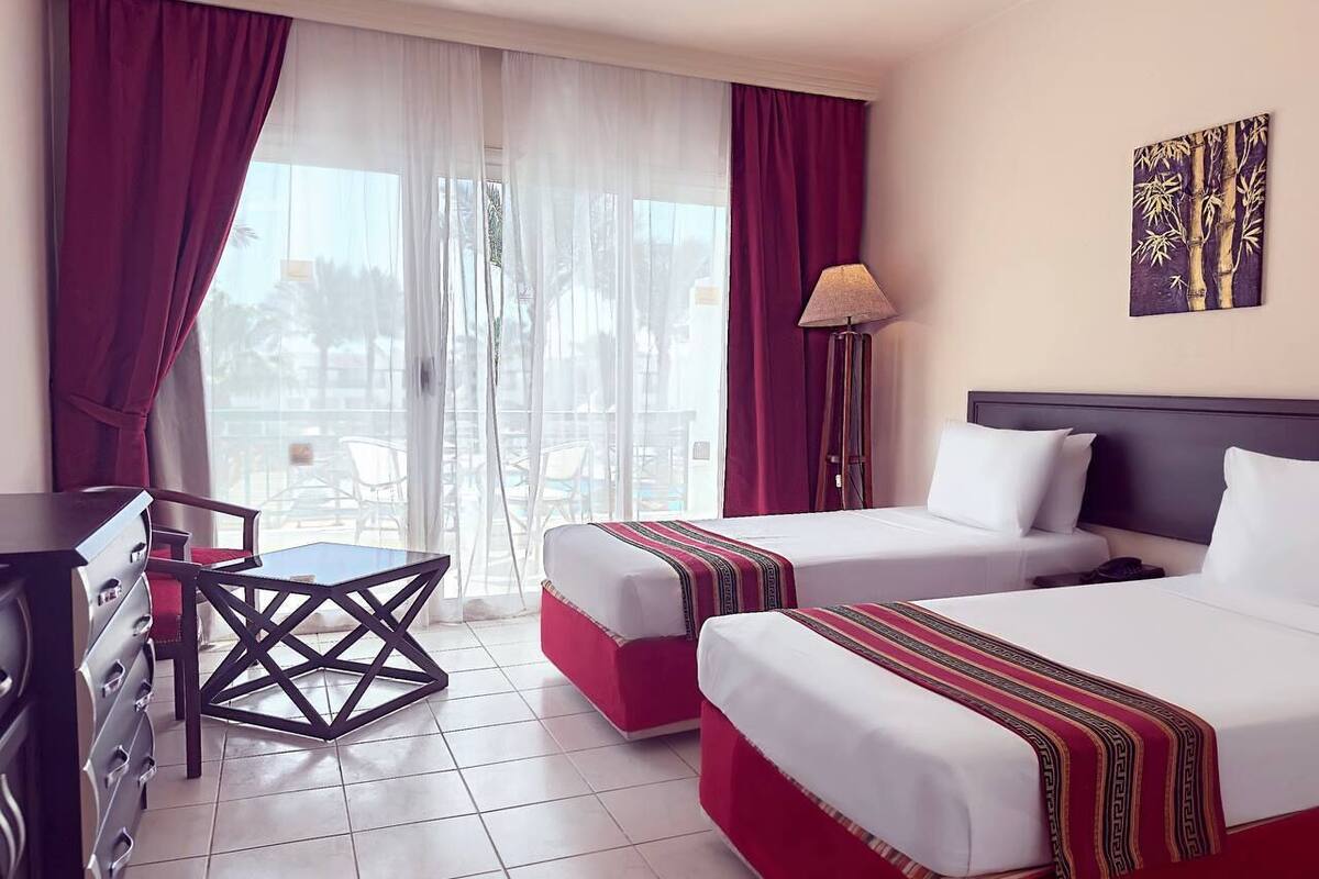 Une chambre d’hôtel avec deux lits, un bureau et une chaise.