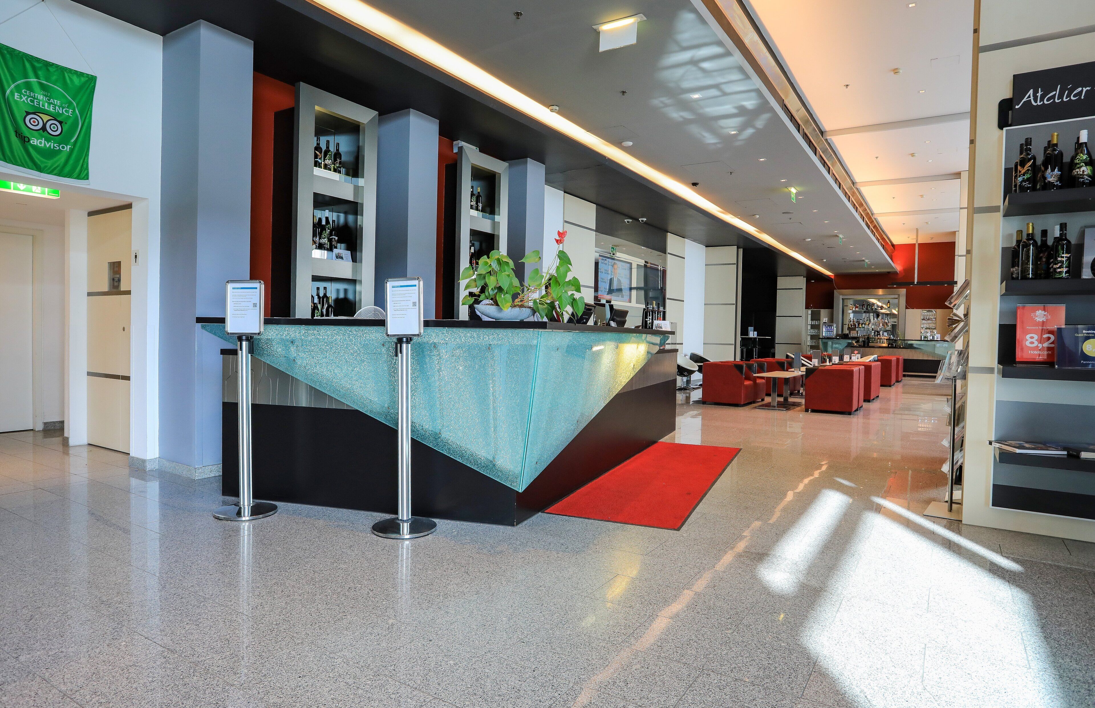 A modern hotel lobby with a reception desk, seating area, and a bar.