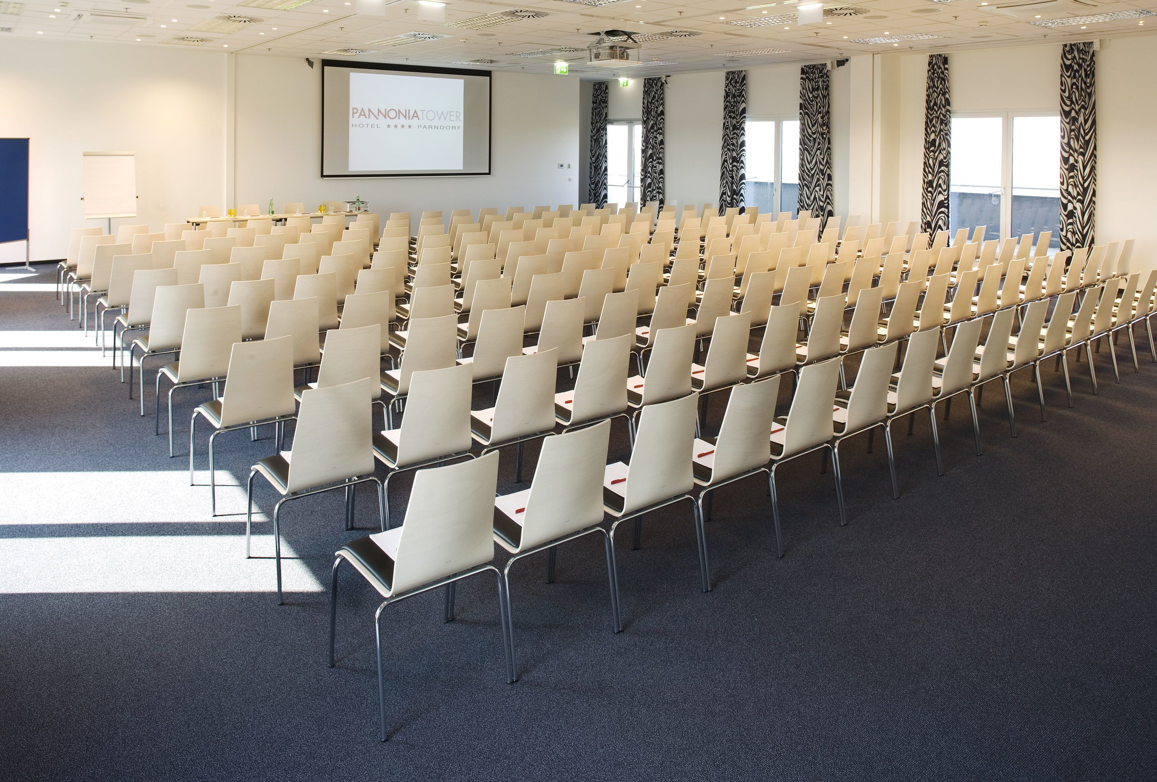 A conference room with rows of chairs, a projector screen, and a whiteboard.