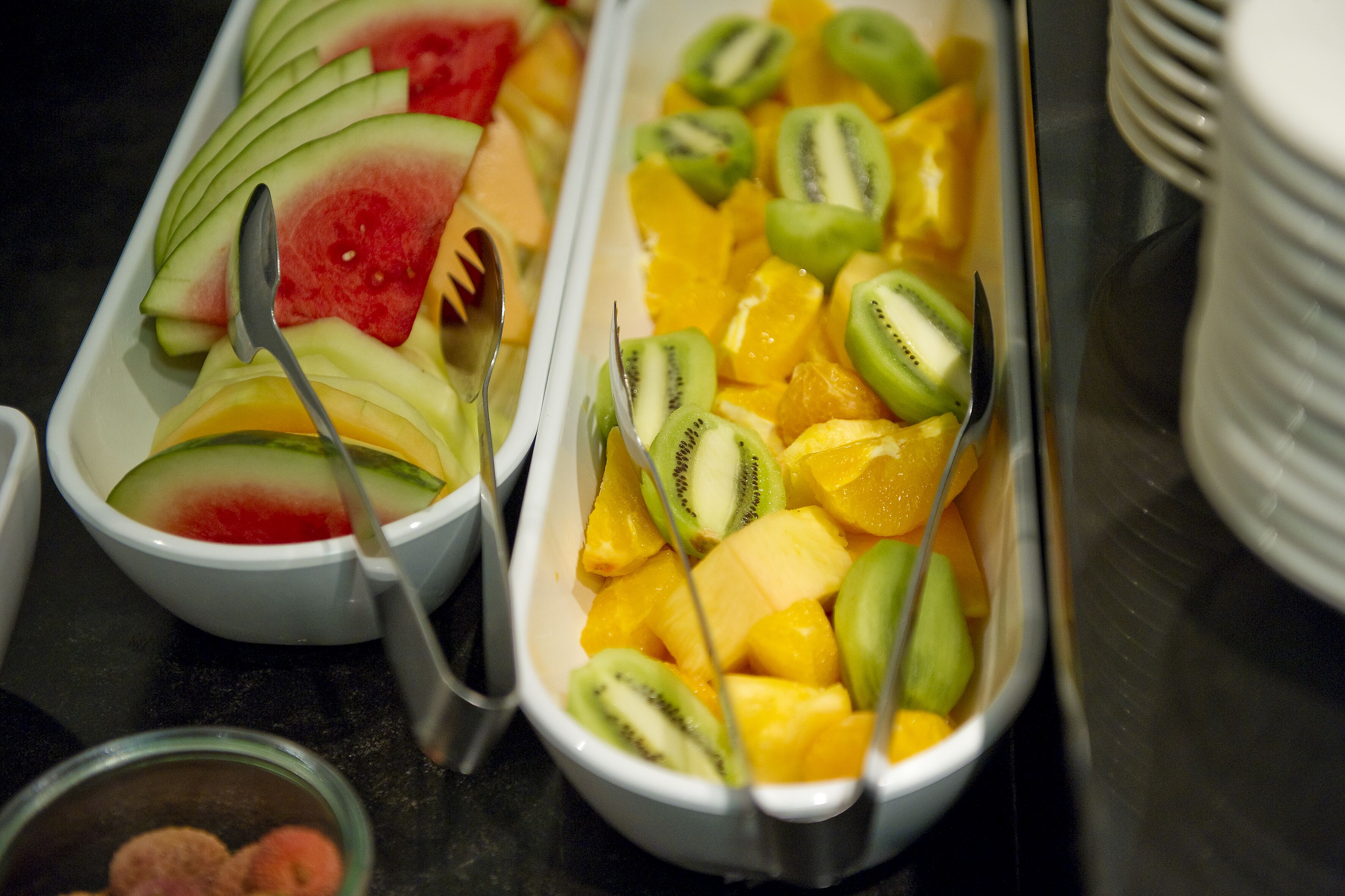 Un buffet proposant une variété de fruits, notamment de la pastèque, des kiwis et des mangues.