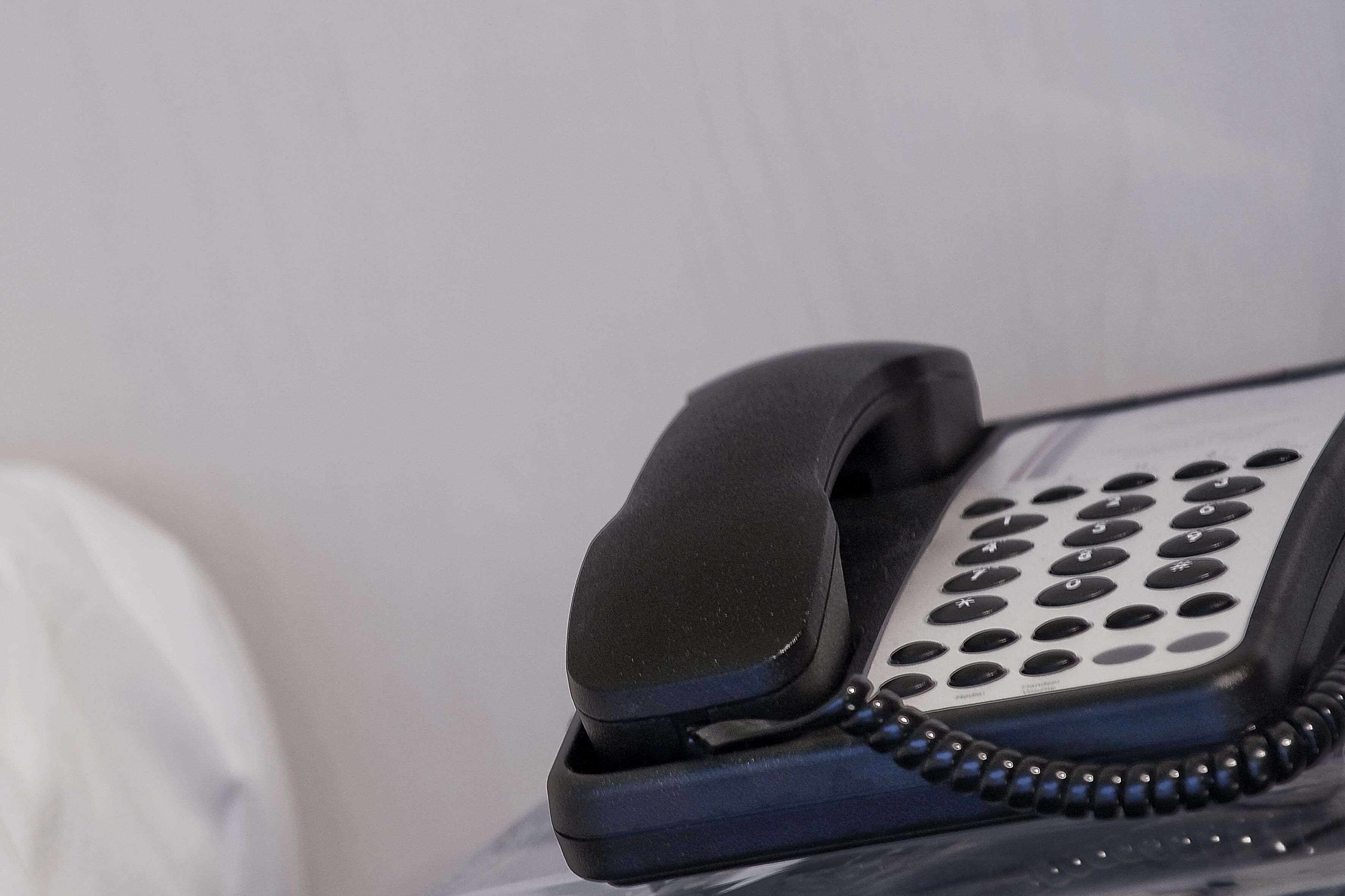A telephone handset with a numeric keypad, connected by a coiled cord.