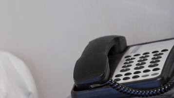 A telephone handset with a numeric keypad, connected by a coiled cord.